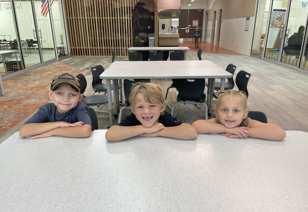 group of 3 students sitting at the table smiling
