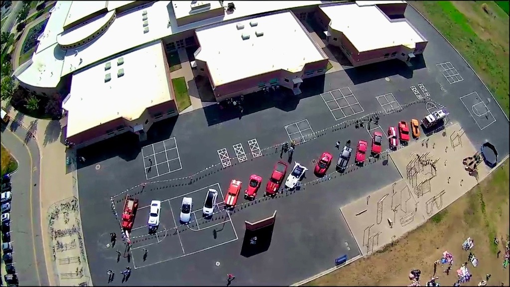drone shot of the school from above and the line of cool cars in the car show