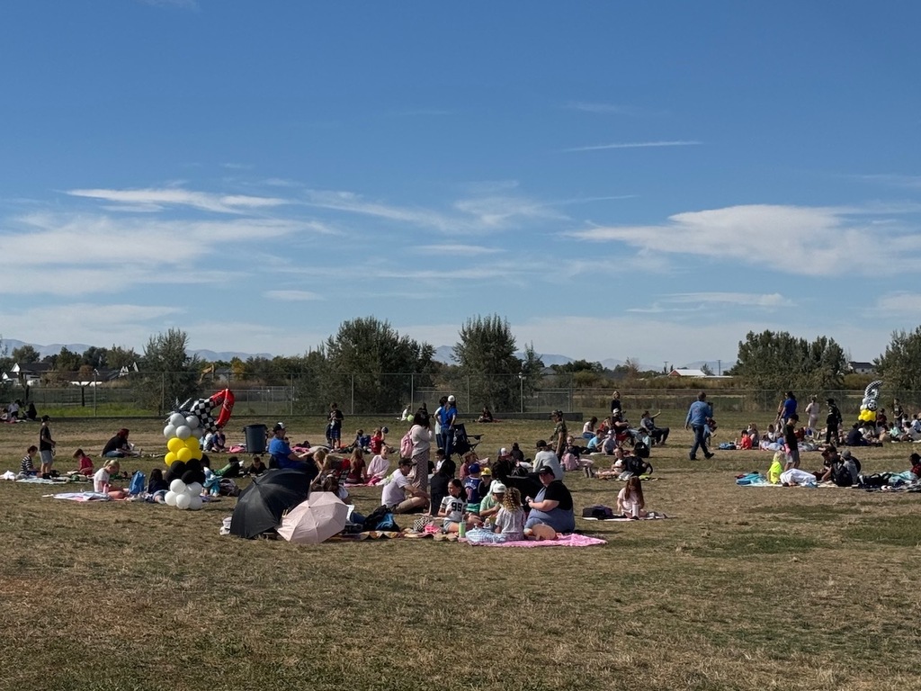 families gathered on the grass of plain city elementary reading, shot is from far away