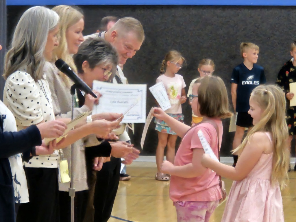 Administrators handing awards to a student wearing pink. 