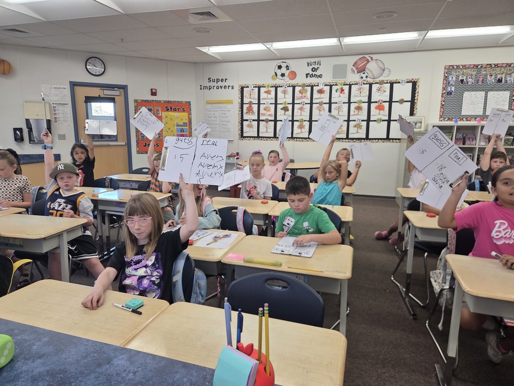 students raising their whiteboards with answers on them