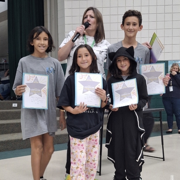 Mrs. Jacobsen and their Reyes kids holding certificates