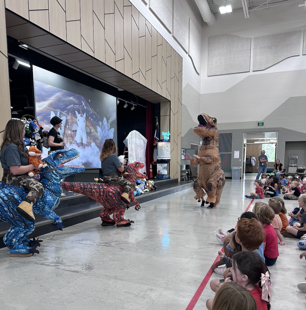 a person in a raptor costume dancing in an assembly
