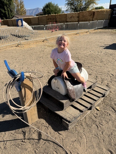 A student grinning on a wooden practice saddle setup.