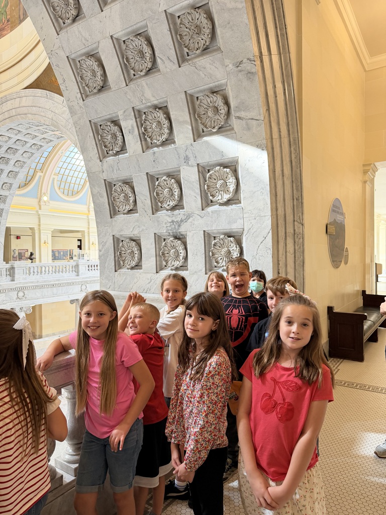 Students standing in a row along a ornate marble hallway inside the Capitol Building.