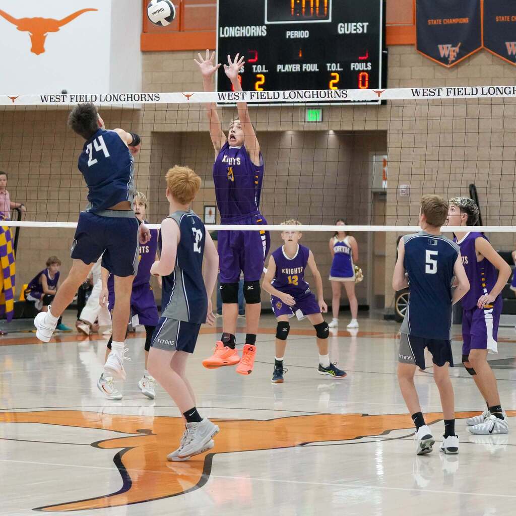 Image 3: An Orion Junior High player going up for a powerful jump-spike over a two-person block at the net.