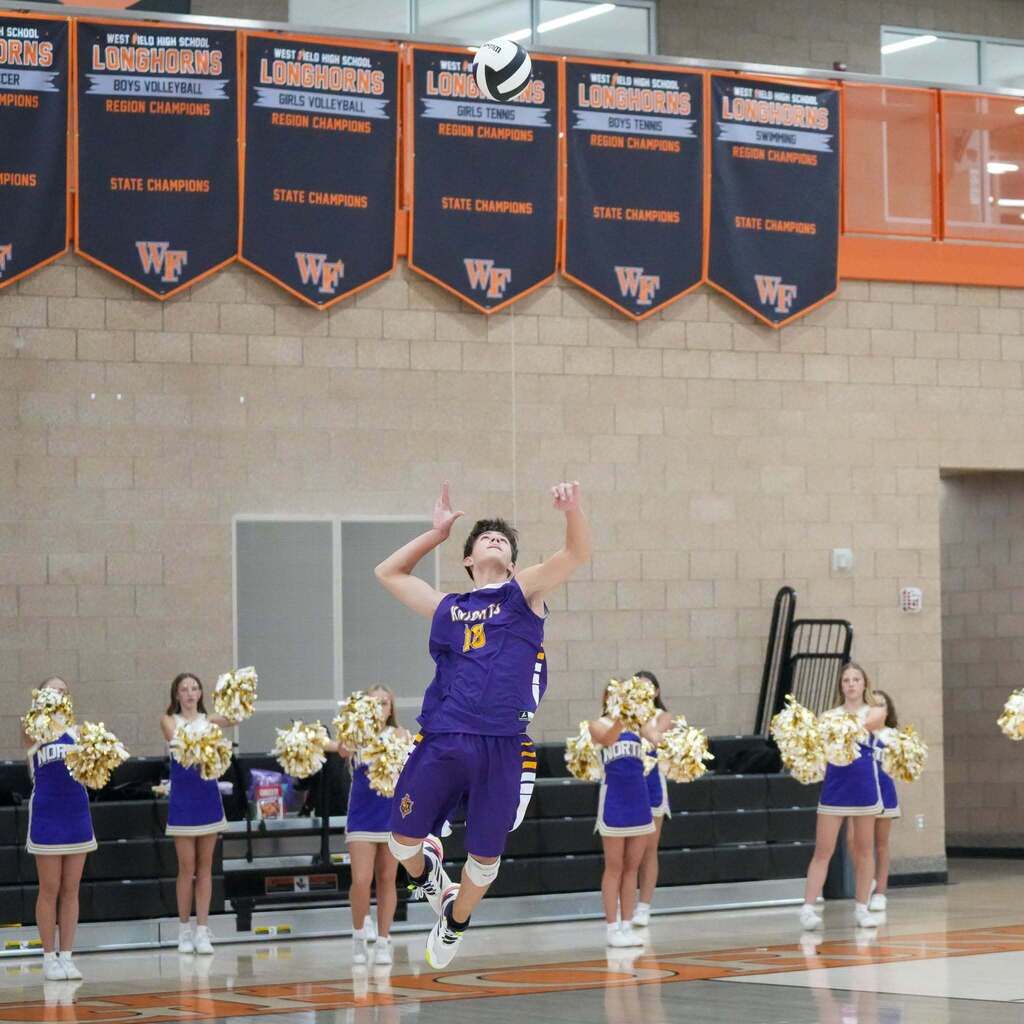 Image 7: A North Ogden Junior High player jumping high to serve the volleyball over the net during competition.