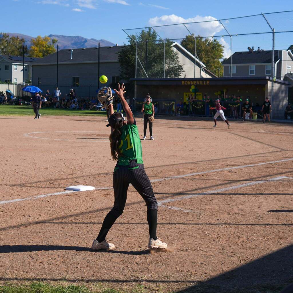 Image 7: An infielder leaping high in the air to field a line drive on the infield dirt.