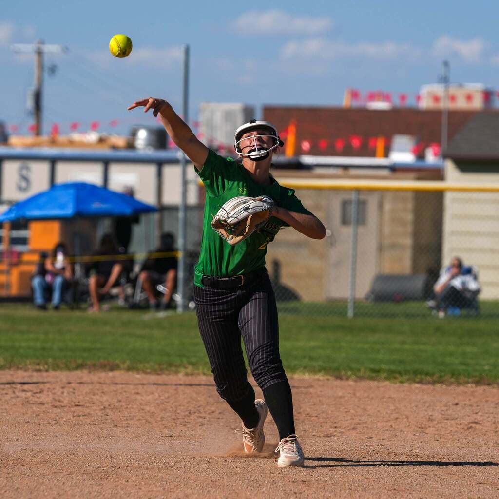 Image 4: An infielder in a green uniform making an athletic, off-balance throw across the diamond.