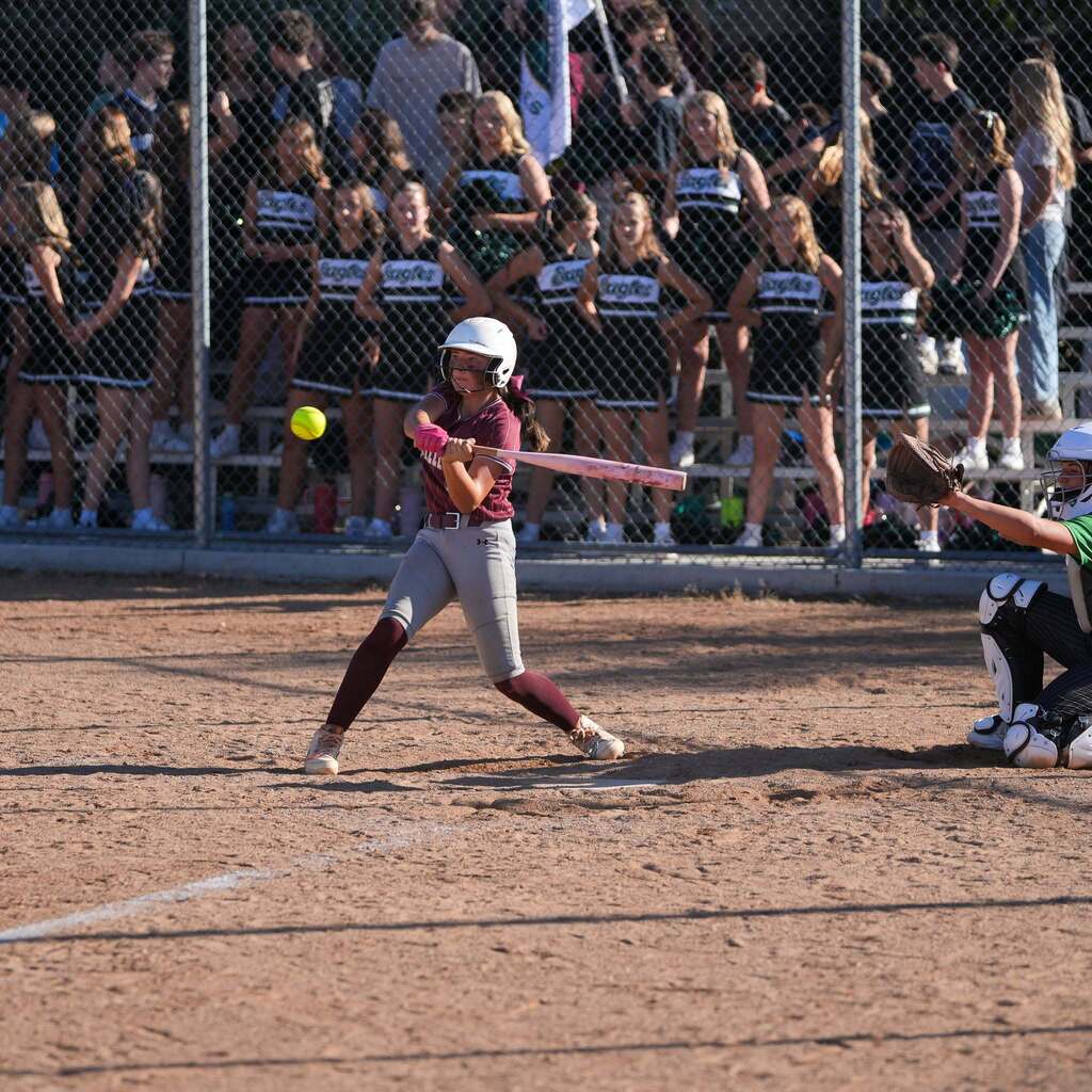 Image 1: A batter in a maroon and grey uniform swinging at a pitch while the catcher poised behind the plate looks on.