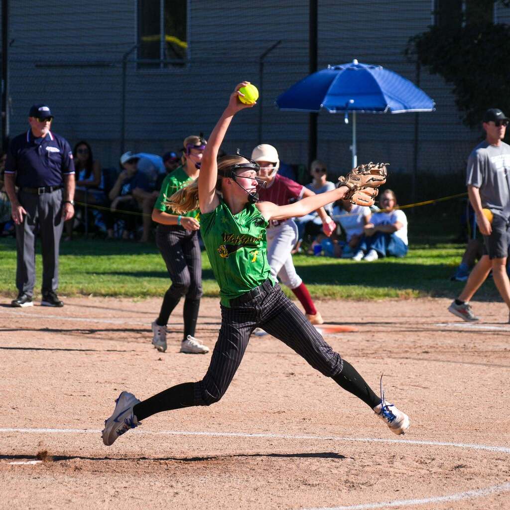 Image 9: A pitcher leaping into her windup delivery with high energy on the mound.
