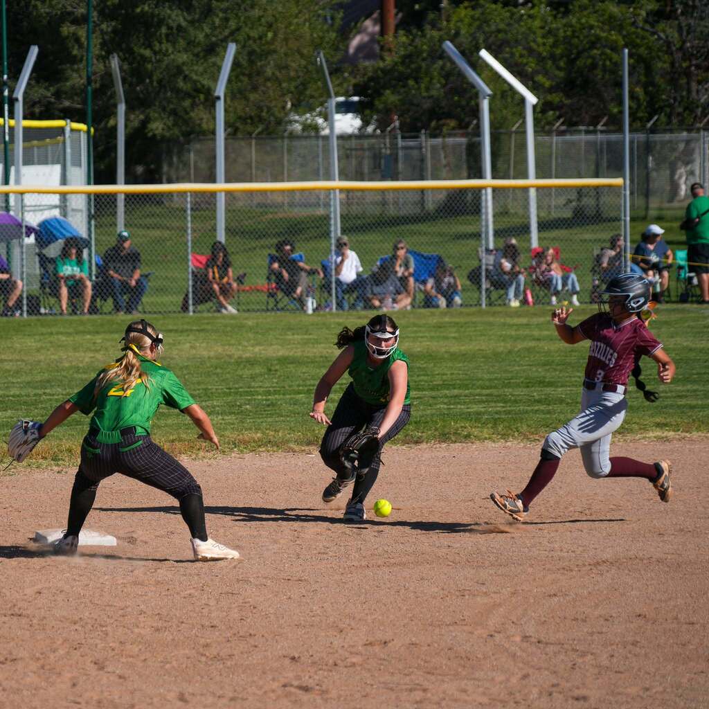 Image 5: A runner diving back to second base as the infielder fields a short hop to attempt a tag.