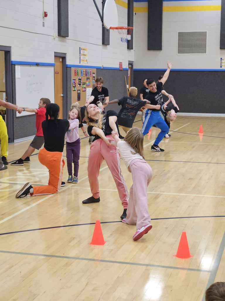 Dancers interacting up-close with students seated on the gym floor during a interactive dance segment.