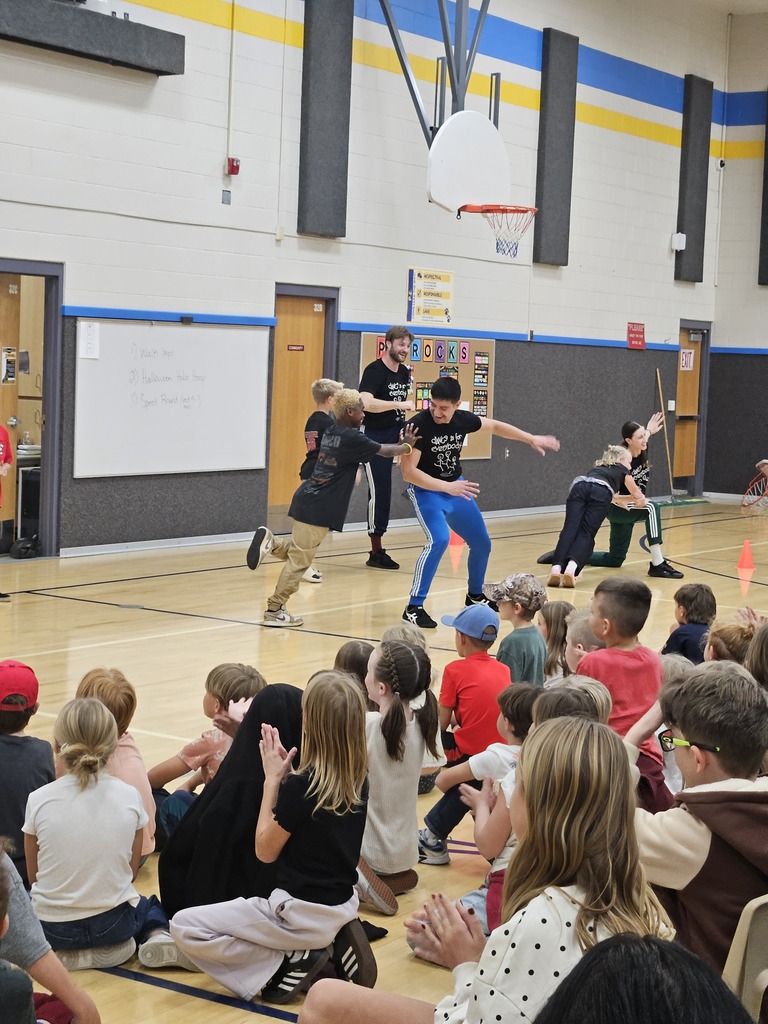 Dancers interacting up-close with students seated on the gym floor during a interactive dance segment.