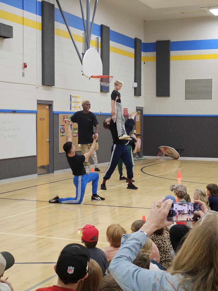 A male dancer executing a high overhead lift with a performer during the dance assembly routine.