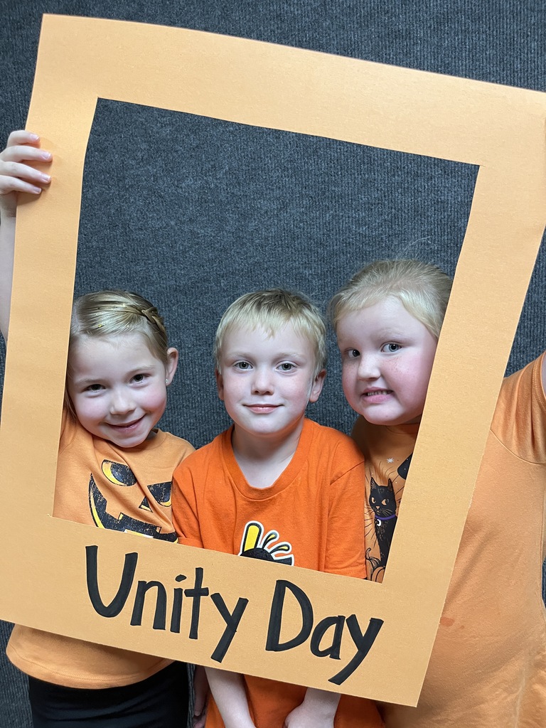 Great shot of three smiling students  posing behind the "Unity Day" frame.