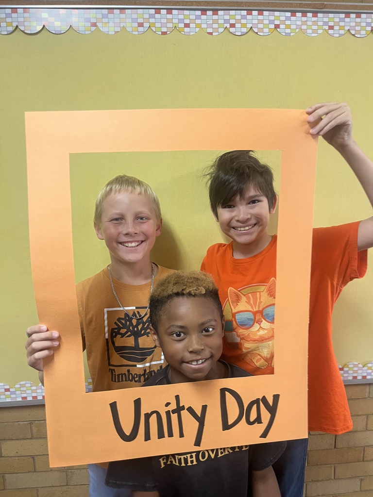 Great shot of smiling students posing behind the "Unity Day" frame.