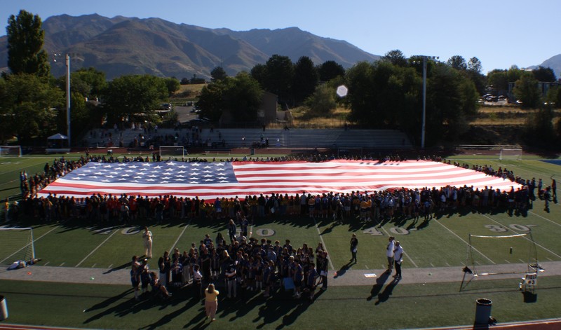 Members of various clubs and organizations at Bonneville unfurl the large flag on the football field as the school choir sings the National Anthem. 