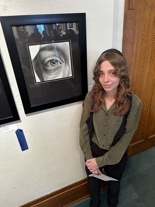 Student poses with art showcase. 