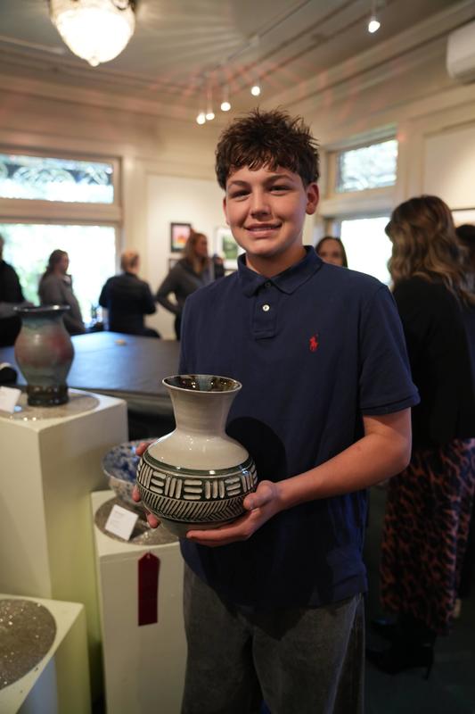 Student poses with art showcase. 