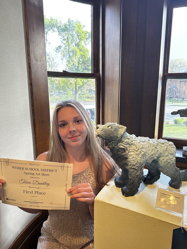 Student poses with art showcase. 