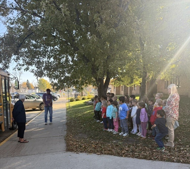bus drivers talking to kindergartners about bus safety outside by bus