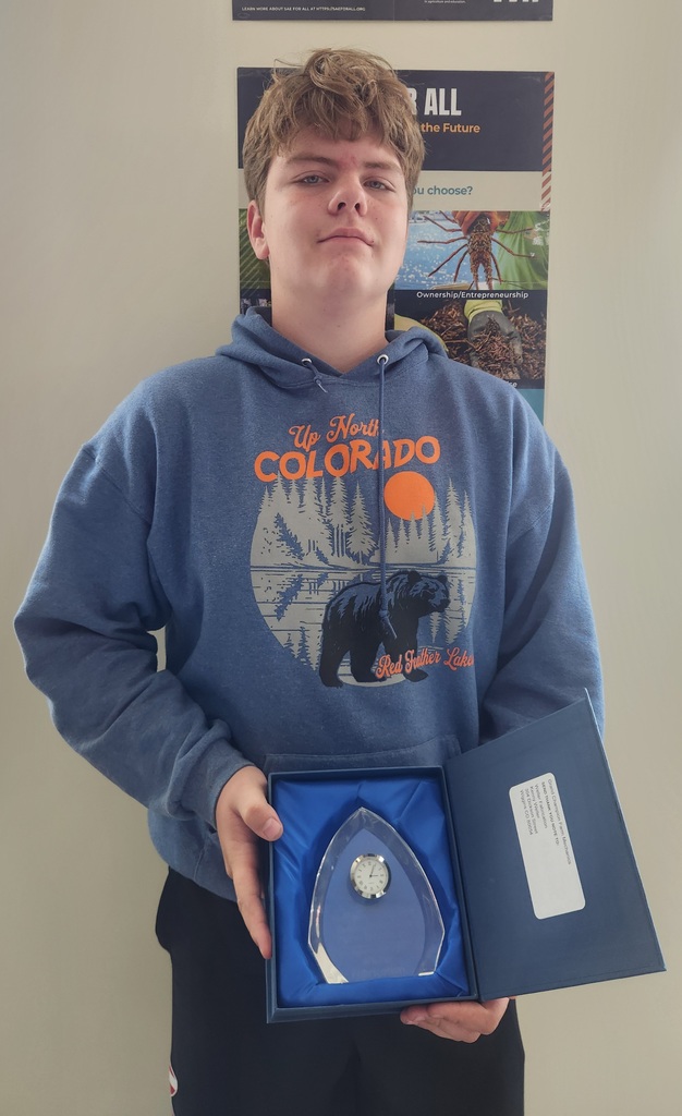 A high school student standing with the award from County Fair for the Ag Mechanics project.