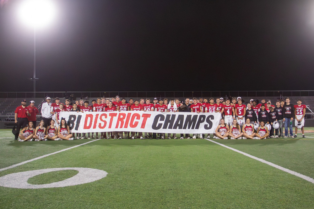 skyrocket football team and cheerleaders pose with a bi-district champs sign with the trophy