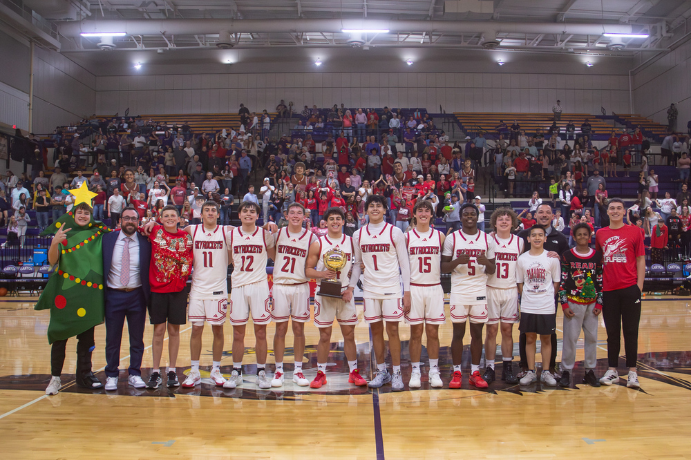 WHS boys basketball pose with the area gold ball with wellington fans in the background