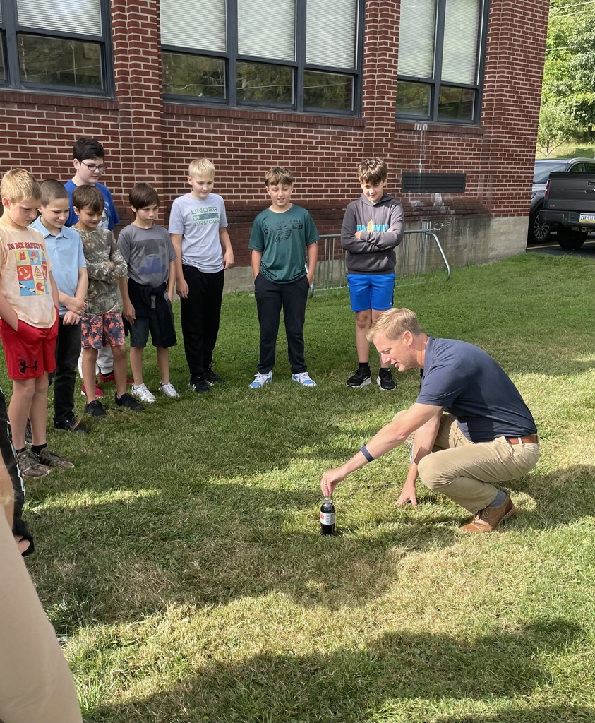 Teacher putting mentos in diet coke with students watching