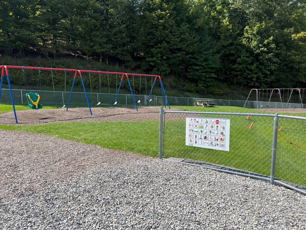 Communication board attached to chain link fence at Charlotte Lappla playground