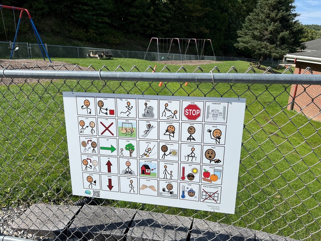 Close up photo of communication board attached to chain link fence on Charlotte Lappla playground