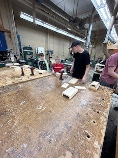Student is receiving help from HS students in building bat box.