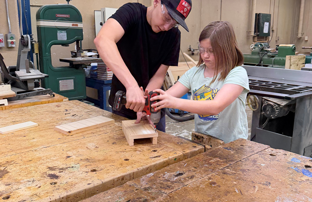 Student helps a girl assemble her bat box.