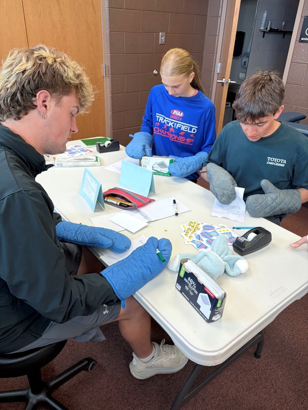 Disability awareness station addressing an envelope with mittens on hands.