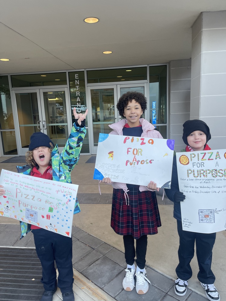 Third graders with signs at carpool to advertise Pizza for a Purpose