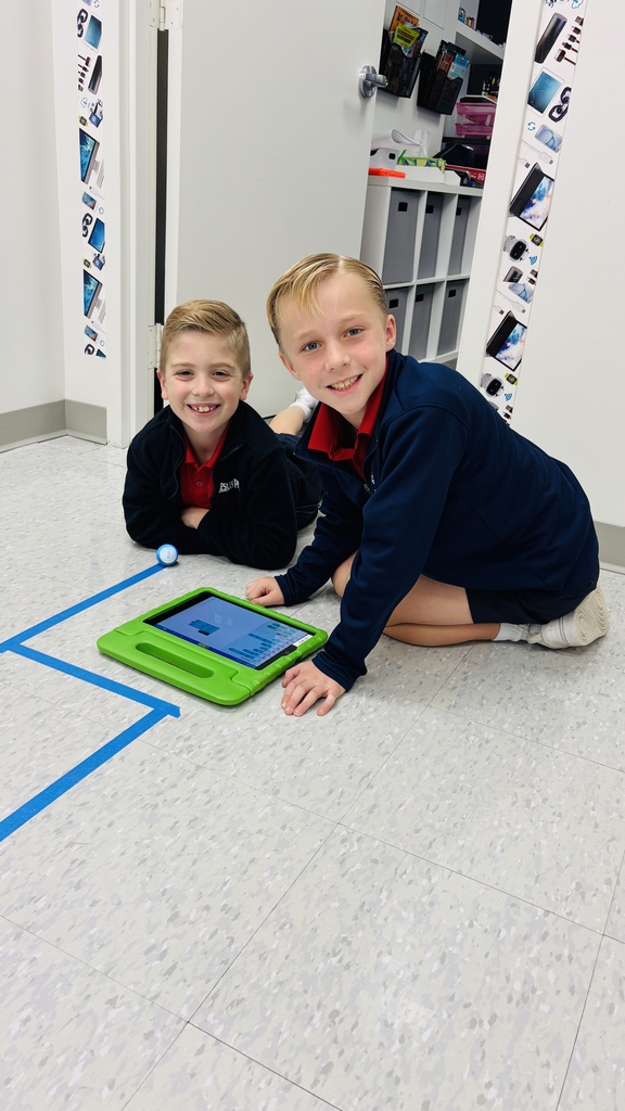 Third graders smiling for a photo as they learn about a robot.