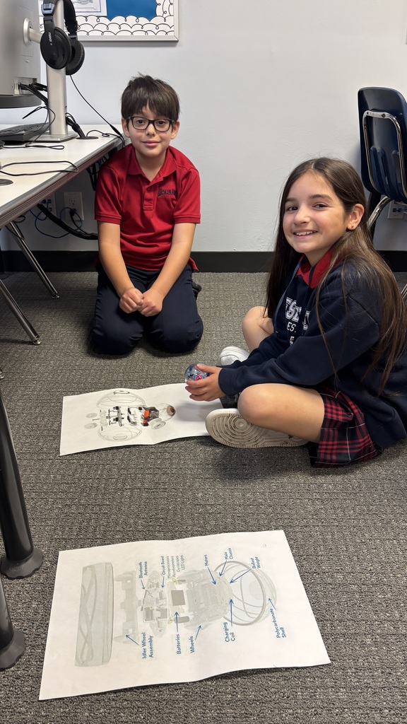 Third graders smiling for a photo as they learn about a robot.
