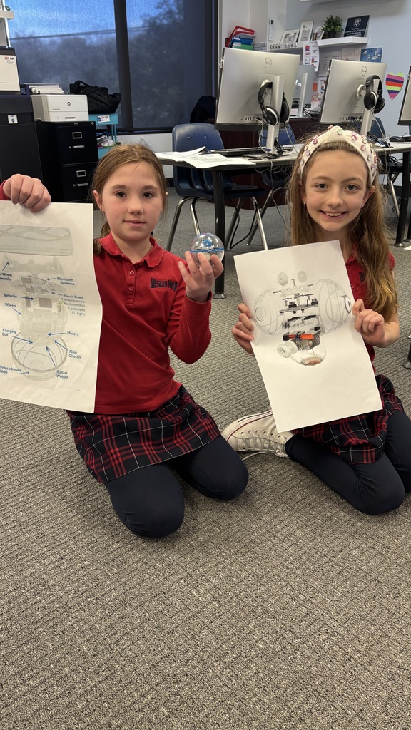 Third graders smiling for a photo as they learn about a robot.