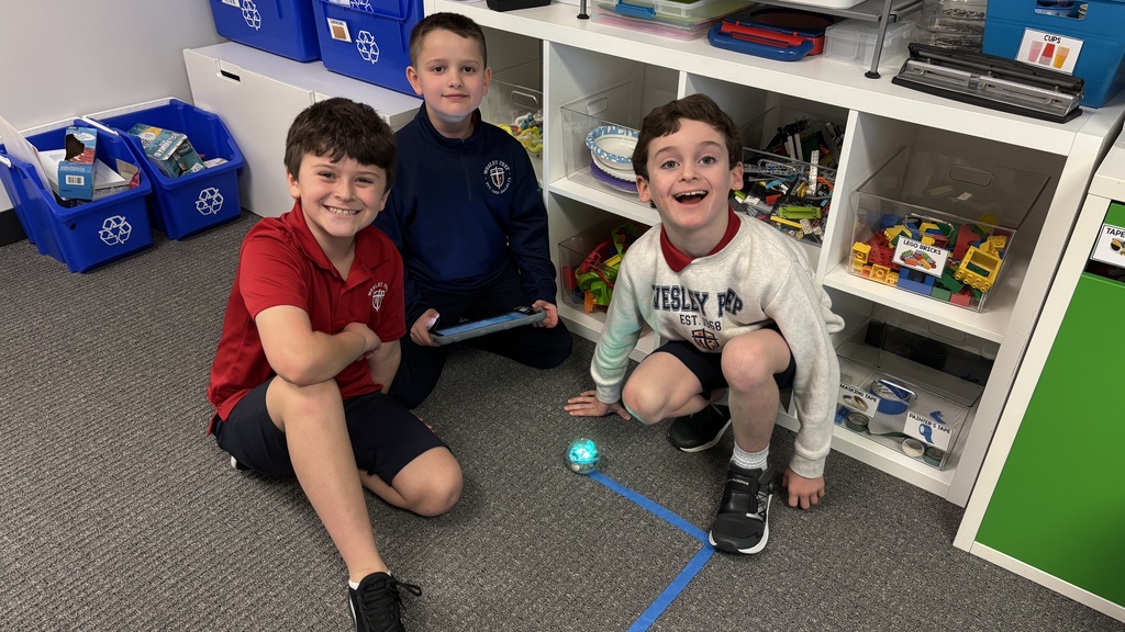 Third graders smiling for a photo as they learn about a robot.