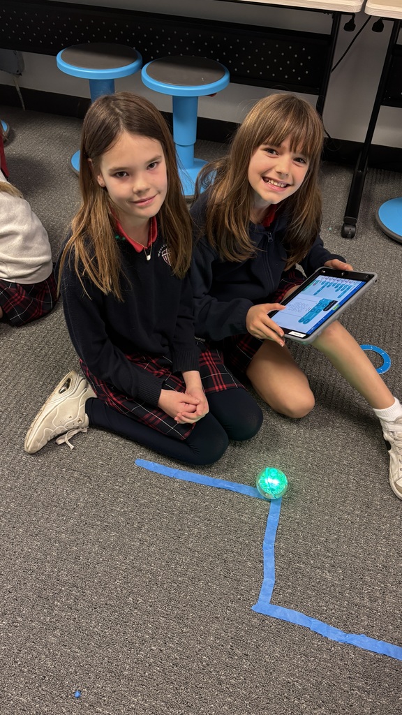 Third graders smiling for a photo as they learn about a robot.