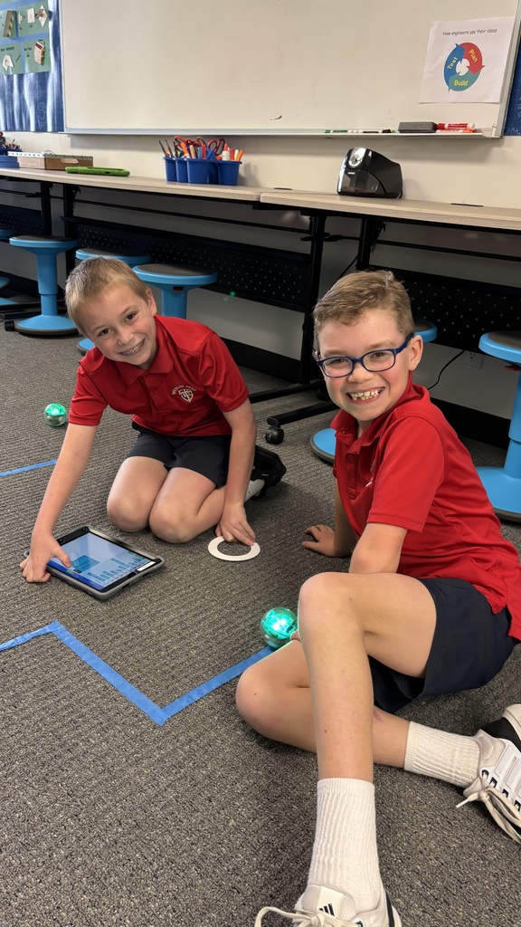 Third graders smiling for a photo as they learn about a robot.