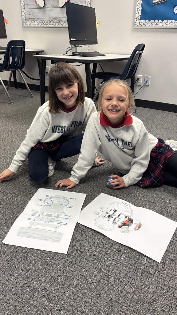 Third graders smiling for a photo as they learn about a robot.