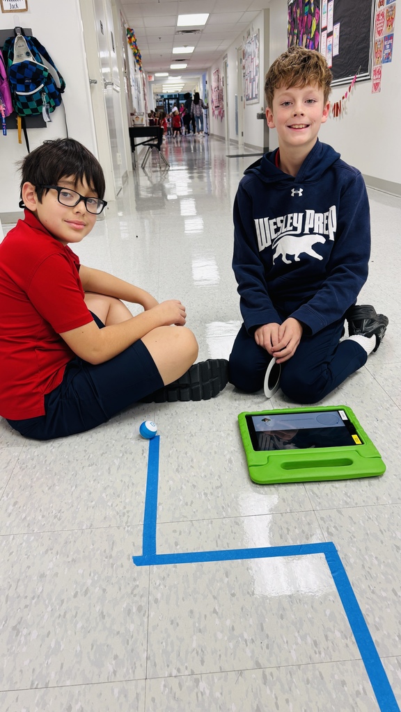 Third graders smiling for a photo as they learn about a robot.