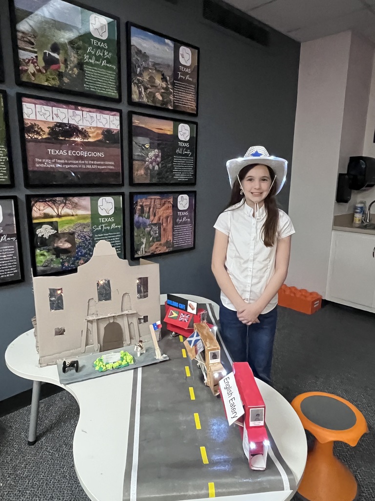 A fourth grader poses with her Alamo project.