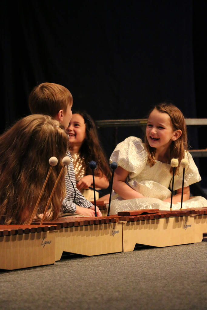 Primer students laugh on stage.