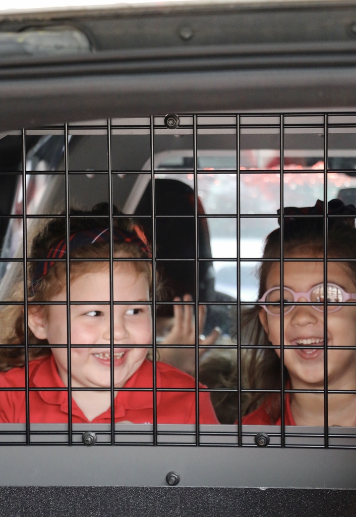 Students laugh and smile in the back of a police car.