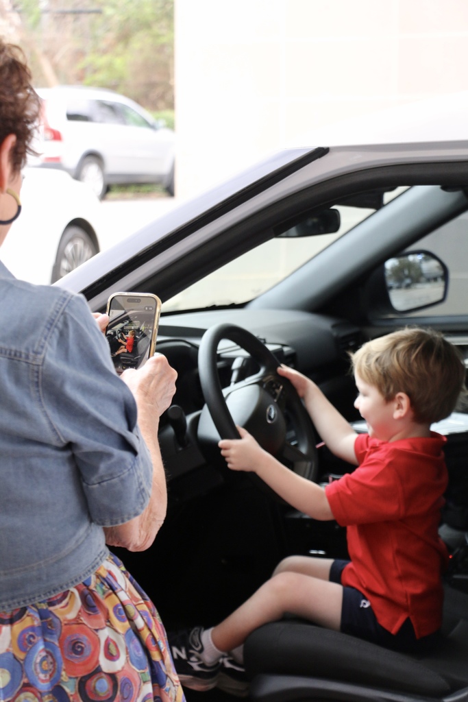 A teacher takes a photo of her student "driving" the police car.