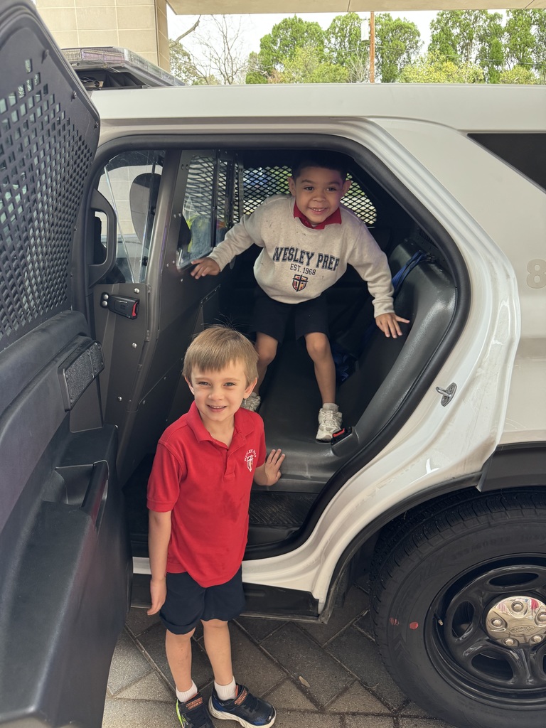 Students smile as they climb around the inside of a police car.