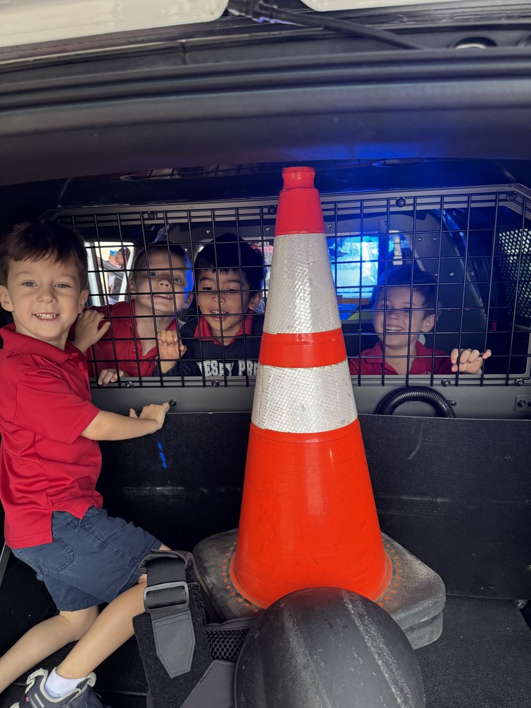 Students have fun exploring the back of a police car.